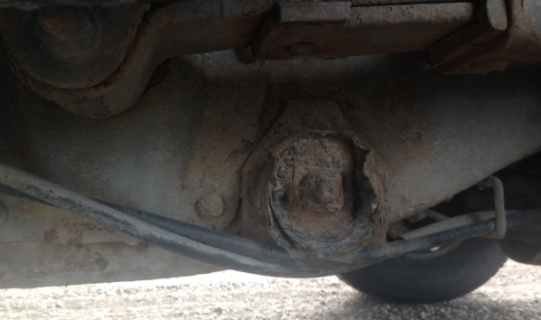 Sitter framför vänster bakhjul. Finns likadan på andra sidan